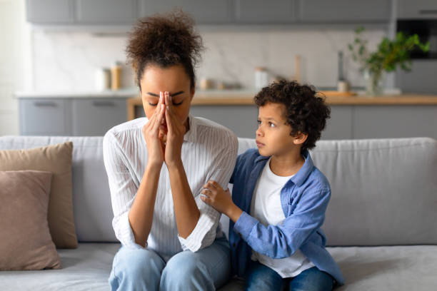 Worried mother with her comforting son in a living room, emotions on display